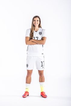 a soccer player poses for a photo in his white uniform and yellow socks with her arms crossed