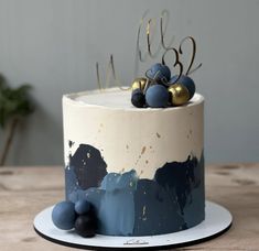 a blue and white cake with gold decorations on top is sitting on a wooden table