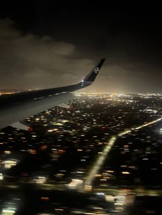 an airplane wing flying over a city at night