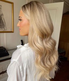 a woman with long blonde hair is standing in front of a desk and looking off into the distance