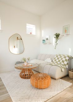 a living room with a white couch and wooden coffee table in front of a round mirror