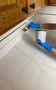 a person in blue gloves painting a kitchen counter