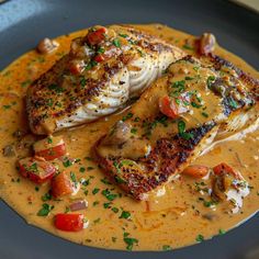 two fish fillets in a creamy sauce on a plate with garnishes