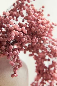 a close up of a vase with pink flowers on the top and bottom, in front of a white background