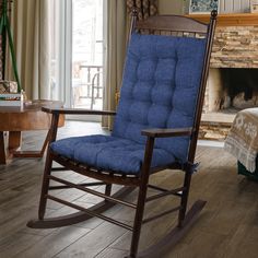 a rocking chair with blue cushions in front of a fireplace