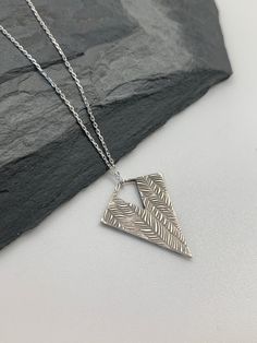 This modern silver triangle necklace  has been entirely handmade using .999 fine silver.  It has been cut from fine silver precious metal clay, textured, fired and oxidized. The pendant hangs from a sterling silver diamond cut cable chain. This fine silver pendant features an embossed  striped feather textured pattern.   Pendant size: approximately 1 x 3/4 inches Chain length: adjustable at 16 and 18 inches                        can also be customized to whatever length needed The necklace is s Necklace Silver Diamond, Silver Diamond Necklace, Contemporary Earrings, Layered Necklaces Silver, Precious Metal Clay, Triangle Necklace, Charm Necklace Silver, Geometric Necklace, Modern Necklaces