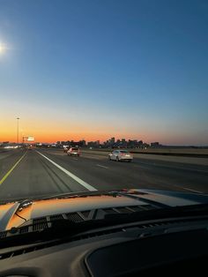 the sun is setting on an interstate highway with cars driving down it and buildings in the distance