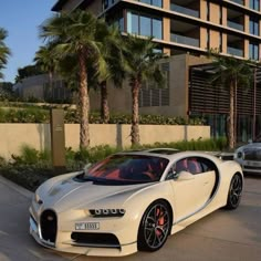 a white bugatti parked in front of a building next to a silver car