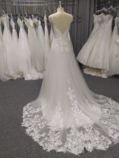 the back of a wedding dress on display in front of other dresses and gowns