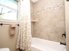 a bathroom with a shower, toilet and bathtub next to a window in it