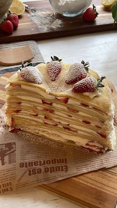 a piece of layered cake sitting on top of a wooden cutting board next to a bowl of strawberries