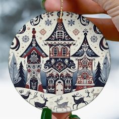 a hand holding up a christmas ornament with a house on it's side