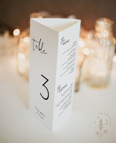 the table numbers are placed on top of each other in front of candles and glass vases