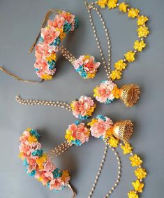 three necklaces with flowers and bells on them sitting on a table next to each other