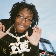 a woman wearing glasses and a necklace with birds on it, posing for the camera