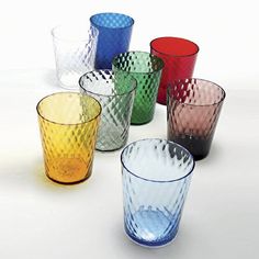 many different colored glass cups on a white surface