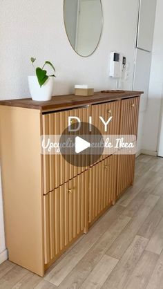 a wooden cabinet sitting on top of a hard wood floor next to a white wall