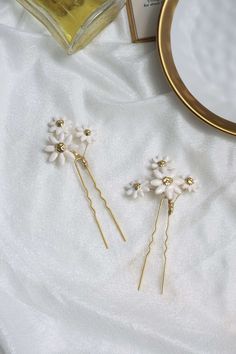 "These hair pins look lovely placed into any hairstyle for any occasion This listing is for a set of two pins. - Lightweight to wear comfortably - Daisies have been hand sculpted from clay - Sealed with a glossy enamel finish for durability - Fixed on gold plated u pins Approximate Measurements including pin: 2\" wide 4.5\" tall ------------------------------------------------- Please keep in mind before purchasing this product is \"MADE TO ORDER\" and has a production time of 1 - 2 weeks + ship Gold Bridal Crowns, Daisy Hair, Golden Hair, Wedding Hair Pins, Gold Halo, Bridal Hair Pins, Bridal Crown, Bridal Tiara, Gold Hair