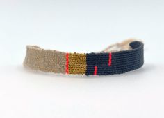 a close up of a wristband on a white surface with red and yellow stripes