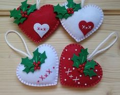 three felt heart ornaments with holly on them