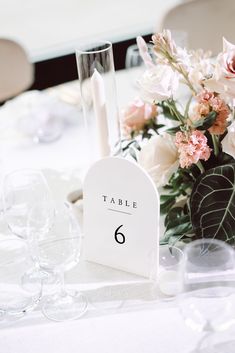 a table with flowers and wine glasses on it, including a sign that says card's gifts