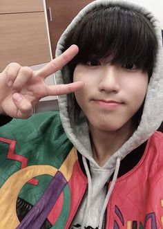 a young boy making the peace sign with his fingers while wearing a hoodie jacket