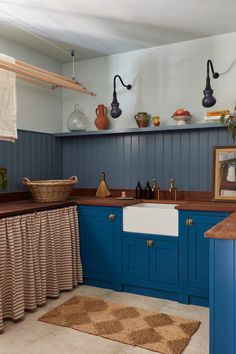 a kitchen with blue cabinets and wooden counter tops, an area rug on the floor