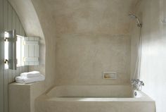 an image of a bathtub with towels on the shelf and in the shower area