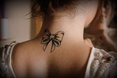 a woman's neck with a bow tattoo on her left side ribcage