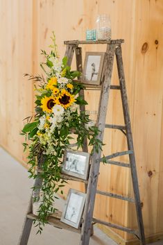 a ladder decorated with sunflowers and greenery next to pictures on the wall