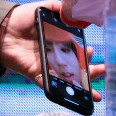 a person holding up a cell phone with a woman's face on the screen