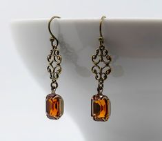 Stunning, elegant but simple Vintage Deco style earrings, designed and crafted in my studio here in the heart of the Isle of Anglesey, N Wales.  Feature a gorgeous ornate Deco style scroll connector with a stunning Vintage Topaz Swarovski cut crystal Rhinestone, captured in a hand set prong bezel cup, with brand new ear wires. I have used Topaz cut crystal for its amazing colour and light reflection, giving grace and elegance to these truly stunning earrings.  Please see photographs for other available colours. Please choose your preferred colour of crystal from the dropdown menu before ordering. Total drop of each earring is 40mm (1.5 inch)  10mm x 8mm vintage Swarovski crystal. Ready for shipping. I take great care wrapping all jewellery in fine soft tissue paper, placed within an organz Giving Grace, Regency Art, Deco Earrings, Bronze Earrings, Handmade Uk, Jewelry Lookbook, Art Deco Earrings, Deco Jewelry, Stunning Earrings