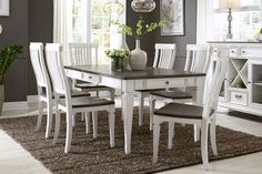 a dining room table with white chairs and a brown rug on the floor in front of it