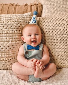 a baby wearing a birthday hat sitting on a couch