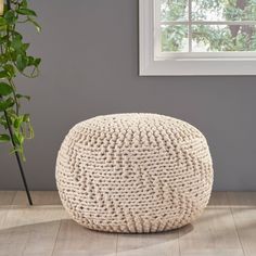 a large white ottoman sitting on top of a wooden floor next to a potted plant