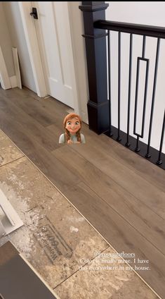 a doll is sitting on the floor in front of a stair case and railings