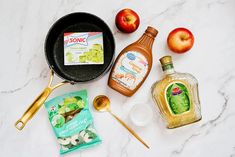 ingredients to make an apple cider recipe laid out on a marble counter top with gold spoons