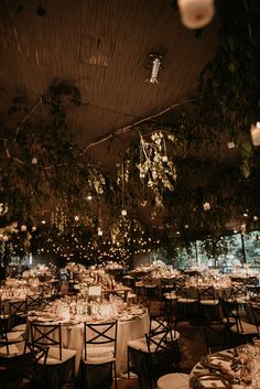 tables and chairs are set up for a formal function with lights hanging from the ceiling