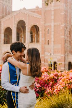 a young man and woman are hugging in front of some colorful flowers at disney world