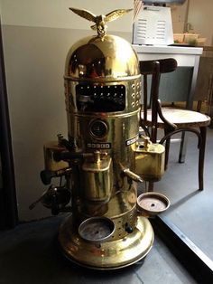 a gold colored coffee machine sitting on top of a table