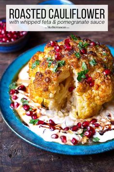 a blue plate topped with cauliflower covered in pomegranate and garnish