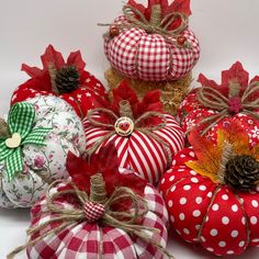 several decorative pumpkins decorated with red and white checkered fabric, pine cone top cones and twine bows