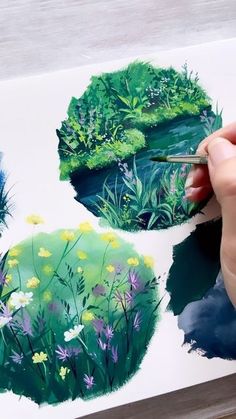 someone is painting flowers and plants on a piece of paper