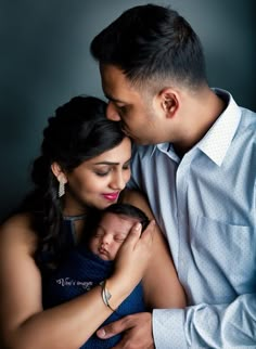 a man and woman holding a baby in their arms