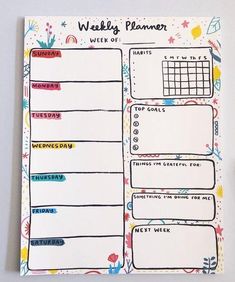 a weekly planner is shown with colorful doodles on the page and flowers around it