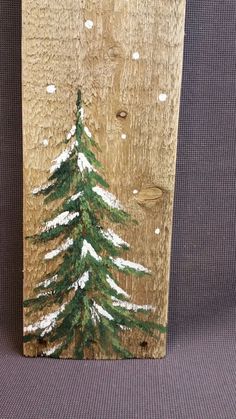 a wooden sign with a pine tree painted on it's side and snow falling off the top