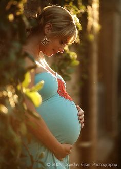 a pregnant woman is standing in the sun