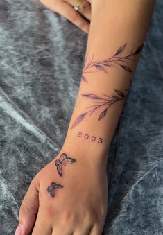 a woman's hand with a tattoo on it that reads 2009 and has leaves