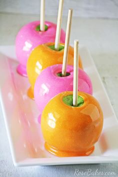 there are four donuts with pink and orange icing on the sticks in the shape of apples