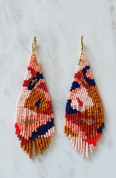 two pairs of beaded earrings on top of a marble counter with white and red beads